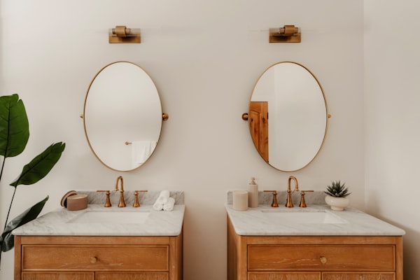 Double vanity bathroom with gold brass fixtures and oval mirrors